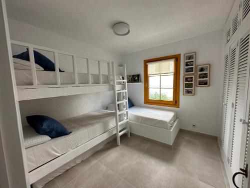 a bedroom with two bunk beds and a window at ALDEAMAR F1 by SOM Menorca in Son Parc