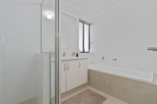 a bathroom with a shower and a tub and a sink at Modern Family Escapes Shopping at your doorstep in Perth