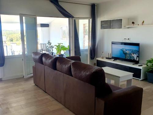 een woonkamer met een bruine bank en een tv bij LA BRISA in Cádiz