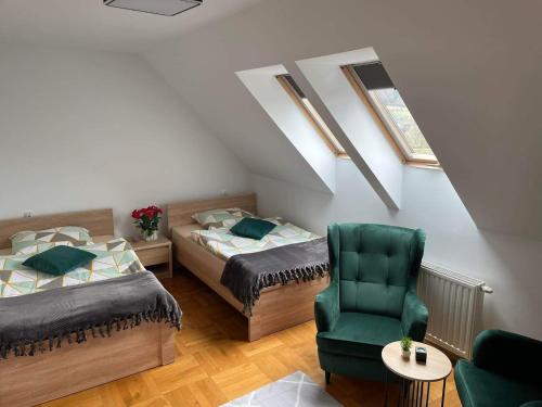 a bedroom with two beds and a green chair at SOBEL II in Tylmanowa