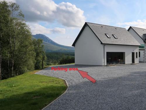 a house with a warning sign on the side of a driveway at Wee Neuk in Spean Bridge