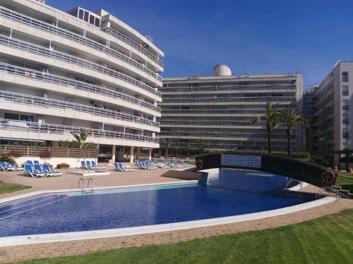 a swimming pool in front of a large building at S'Abanell Central Park seafront apartment in Blanes