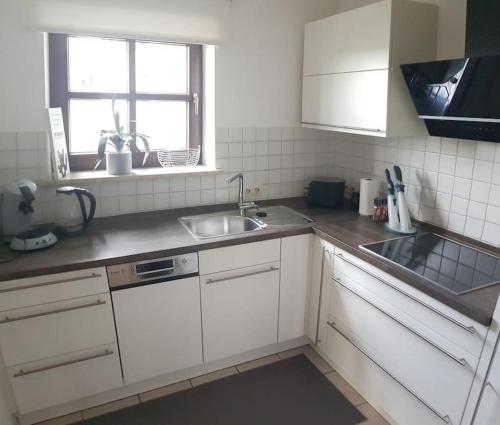 a kitchen with white cabinets and a sink and a window at City-close oasis in the green in Deggendorf
