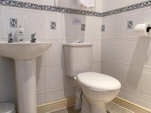 Baño blanco con aseo y lavamanos en No 6 Quality Guesthouse, en Llandudno