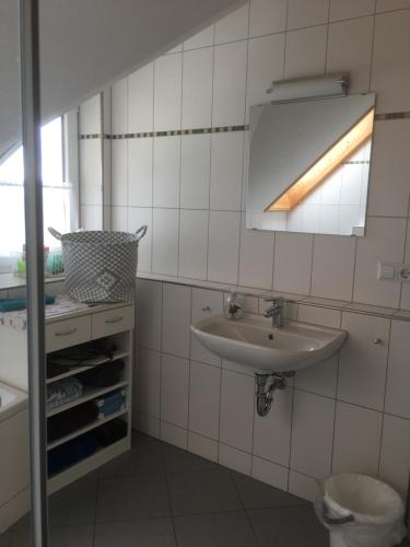 a white tiled bathroom with a sink and a window at Ferienwohnung Arnika 