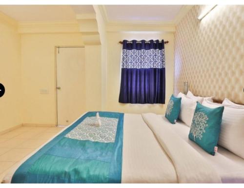a bedroom with a large bed with blue and white pillows at Hotel Grand Apple, Ahmedabad in Ahmedabad