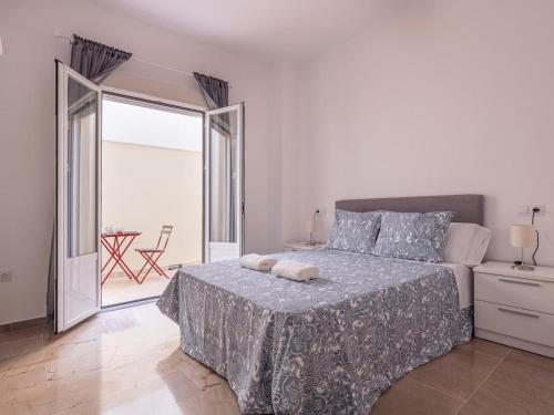 a white bedroom with a bed and a balcony at Alcalá del Rio! bajo A in Alcalá del Río