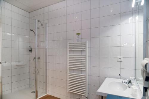 a white tiled bathroom with a shower and a sink at Quadraverde in Lyon