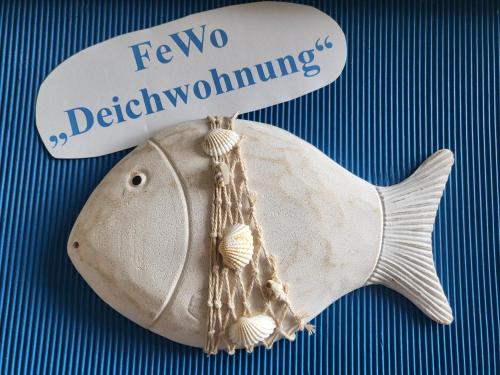 Ein weißer Fisch mit einem Schild drauf. in der Unterkunft Ferienwohnungen Brasse in Dornumersiel