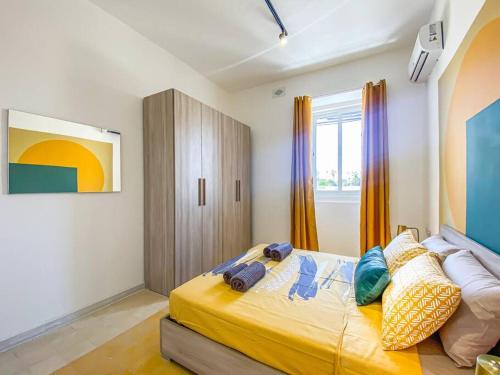 a bedroom with a bed with yellow sheets and a window at First floor 2 bedroom Modern Apartment in Gzira 3 in Il-Gżira