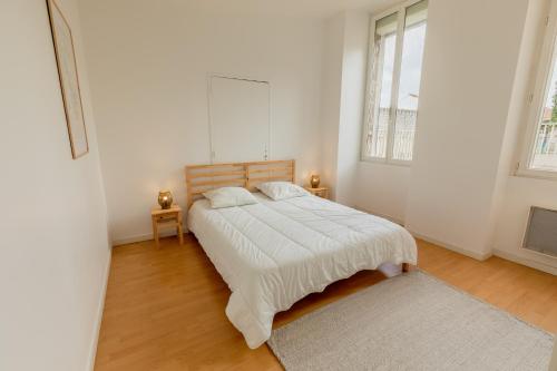 a white bedroom with a bed and two windows at - Le Saugeron - in Blaye