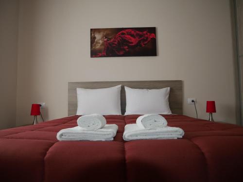 Un dormitorio con una cama roja con toallas. en Roza's Family House, en Imerovigli