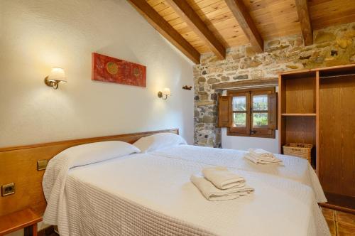 Un dormitorio con una cama blanca con toallas. en Mas Molera Turisme Rural, en Sant Joan les Fonts