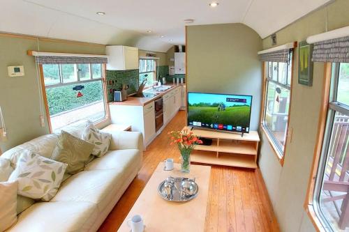 a living room with a white couch and a tv at Carriage 2 - Coalport Station Holidays in Telford