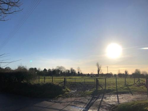 a sun setting over a field with a fence at Stylish Cottage in the Pewsey Vale in Marlborough