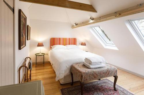 a bedroom with a white bed and two windows at Stylish Cottage in the Pewsey Vale in Marlborough