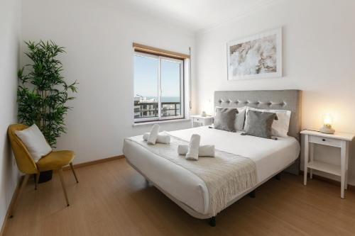 a white bedroom with a large bed and a chair at Green Hill in Nazaré