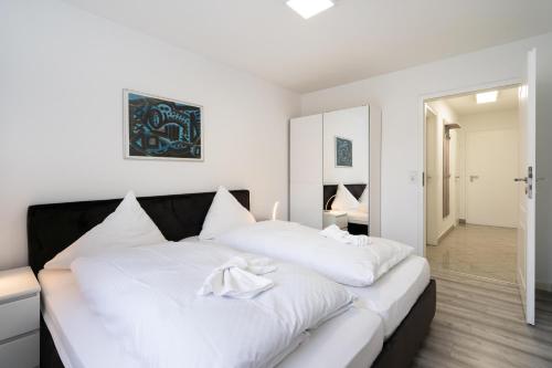 a white bedroom with a large bed with white sheets at Albatros EG in Tinnum