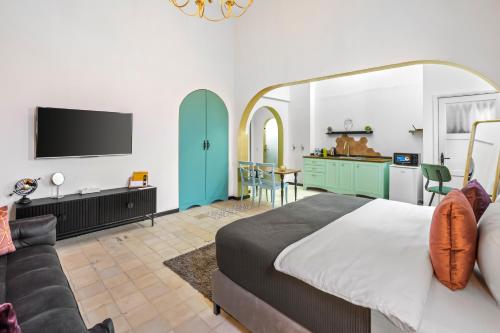 een slaapkamer met een bed, een bank en een tv bij מלון הליוס בוטיק מרשת מלונות לה פינקה in Beer Sheva