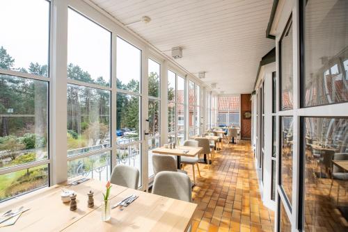 a restaurant with tables and chairs and large windows at Hotel Wehrburg in Cuxhaven