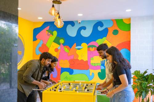 eine Gruppe von Menschen spielt Schach vor einer bunten Wand in der Unterkunft The Social Stays Jaipur formerly ArtBuzz in Jaipur