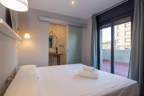 una camera da letto con un letto bianco con una grande finestra di BeBarceloner Sant Andreu Apartments - 1 bedroom with terrace a Barcellona