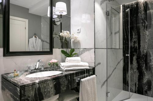 uma casa de banho com um lavatório e um chuveiro com um espelho. em Emperador em Madrid