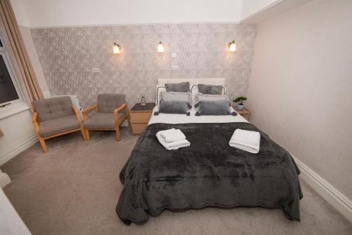 a large bedroom with a large bed and two chairs at Blantyre Guest House in Bridlington