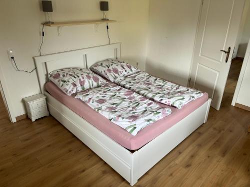 a bed with a white frame and a pink and white blanket at Heckenstübchen in Simmerath