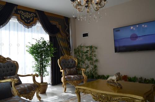 a living room with two chairs and a table and a tv at Coisin Royal Hotel in Arnavutköy