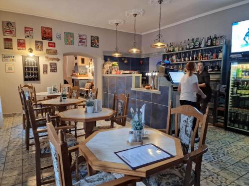 a woman standing in a restaurant with tables and chairs at Penzión na Trojice & Reštaurácia FORTUNE in Banská Štiavnica