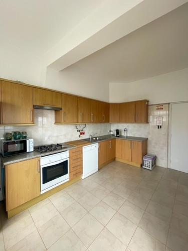 a large kitchen with wooden cabinets and white appliances at LINHA D ÁGUA - ap in Salema