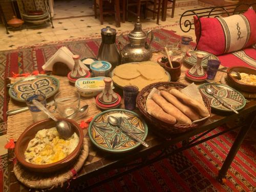 einen Tisch mit Teller mit Essen und Brot darauf in der Unterkunft RIAD SULTAN Marrakech in Marrakesch