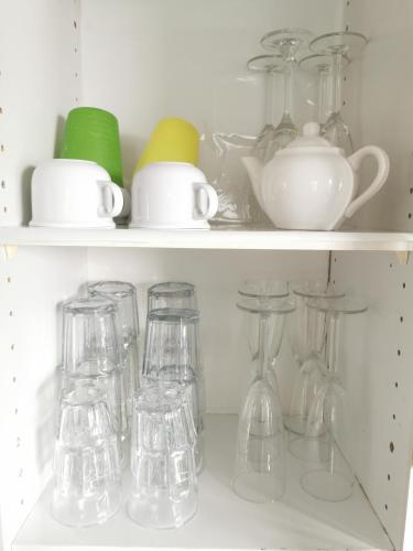 a shelf filled with glasses and other glass items at Sydney Meets Miranda, Comfy 4 Bedrooms Corner House in Miranda
