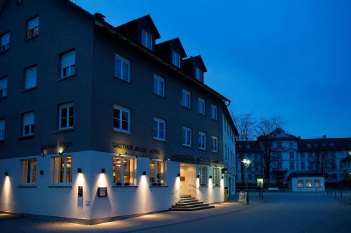 un bâtiment avec des lumières devant lui la nuit dans l'établissement Gasthof Adler, à Bad Wurzach