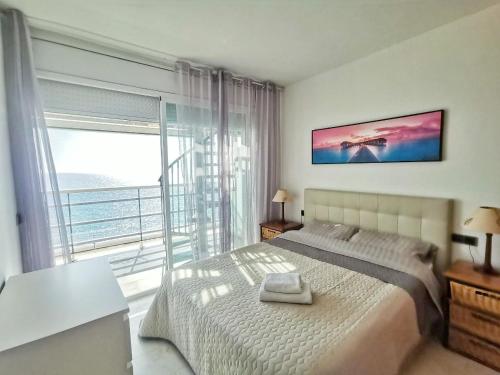 a bedroom with a bed and a large window at Seafront apartment in Blanes in Blanes