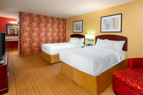 a hotel room with two beds and a red couch at Courtyard by Marriott Junction City in Junction City
