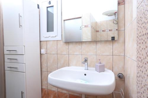 a bathroom with a white sink and a mirror at Irene house tenis club in Agios Rokkos