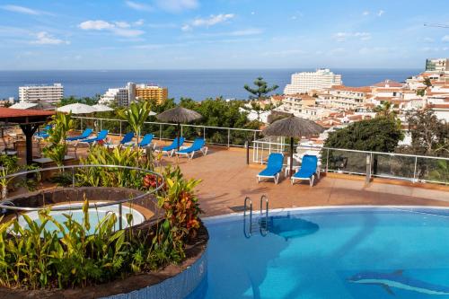 a resort with a swimming pool and chairs and the ocean at Wyndham Residences Costa Adeje in Adeje