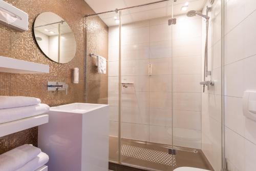 a bathroom with a glass shower and a sink at Amrâth Airport Hotel Rotterdam, BW Signature Collection in Rotterdam
