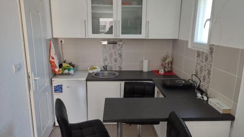 a small kitchen with white cabinets and a black counter top at Studio Centar in Petrovac na Mlavi