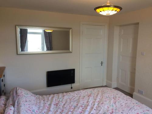 a bedroom with a bed and a flat screen tv at Beautiful Apartment in Character Former Rectory in Penrith