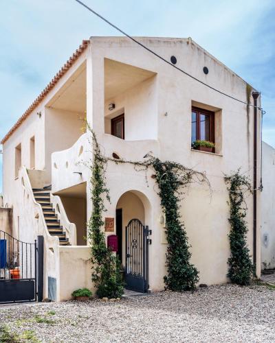 una casa bianca con cancello e scale di Domo Mea Terra e Domo Mea Chelu - Comfort nel centro storico di Orosei a Orosei