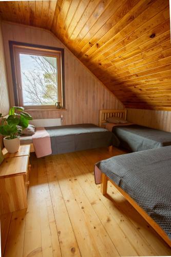 a attic room with two beds and a window at Rāznas Stāvkrasti in Kaunata