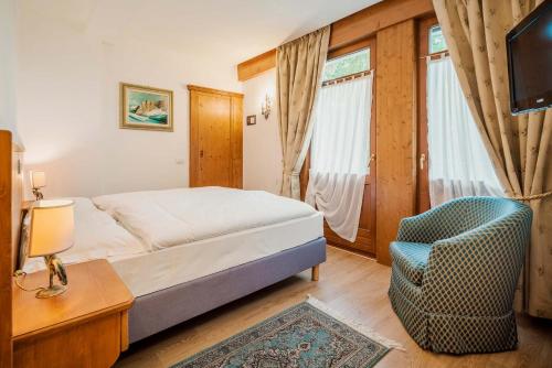a bedroom with a bed and a chair and a television at Franceschi Park Hotel in Cortina dʼAmpezzo
