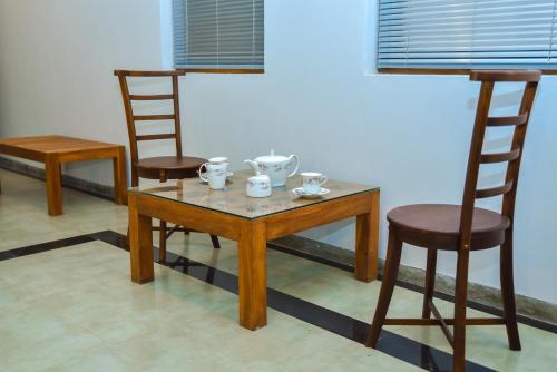 Tectona Grandis By Travel Corners في غامباها: طاولة عليها كرسيين وطاولة عليها أكواب