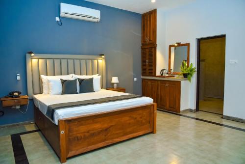 a bedroom with a bed and a blue wall at Tectona Grandis - Negombo in Gampaha