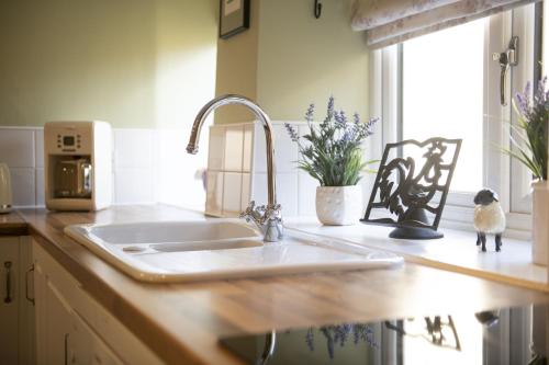 a kitchen counter with a sink and a window at Burn Cottage in Leyburn
