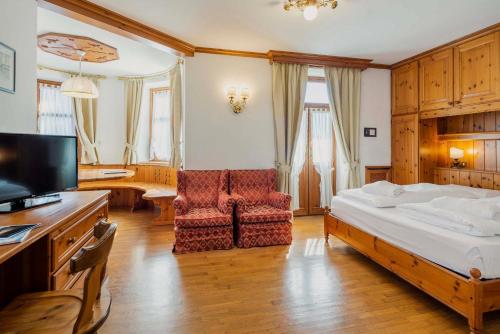 a bedroom with a bed and a chair and a television at Franceschi Park Hotel in Cortina dʼAmpezzo