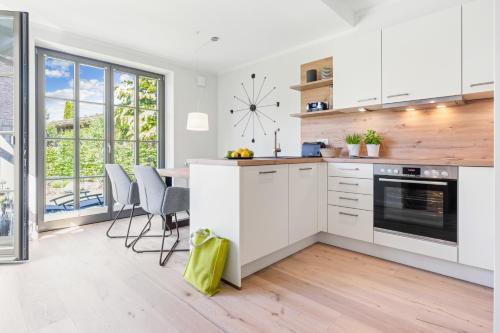 青斯特FeWo Brede Zingst的厨房里有白色的橱柜，墙上挂着一个钟